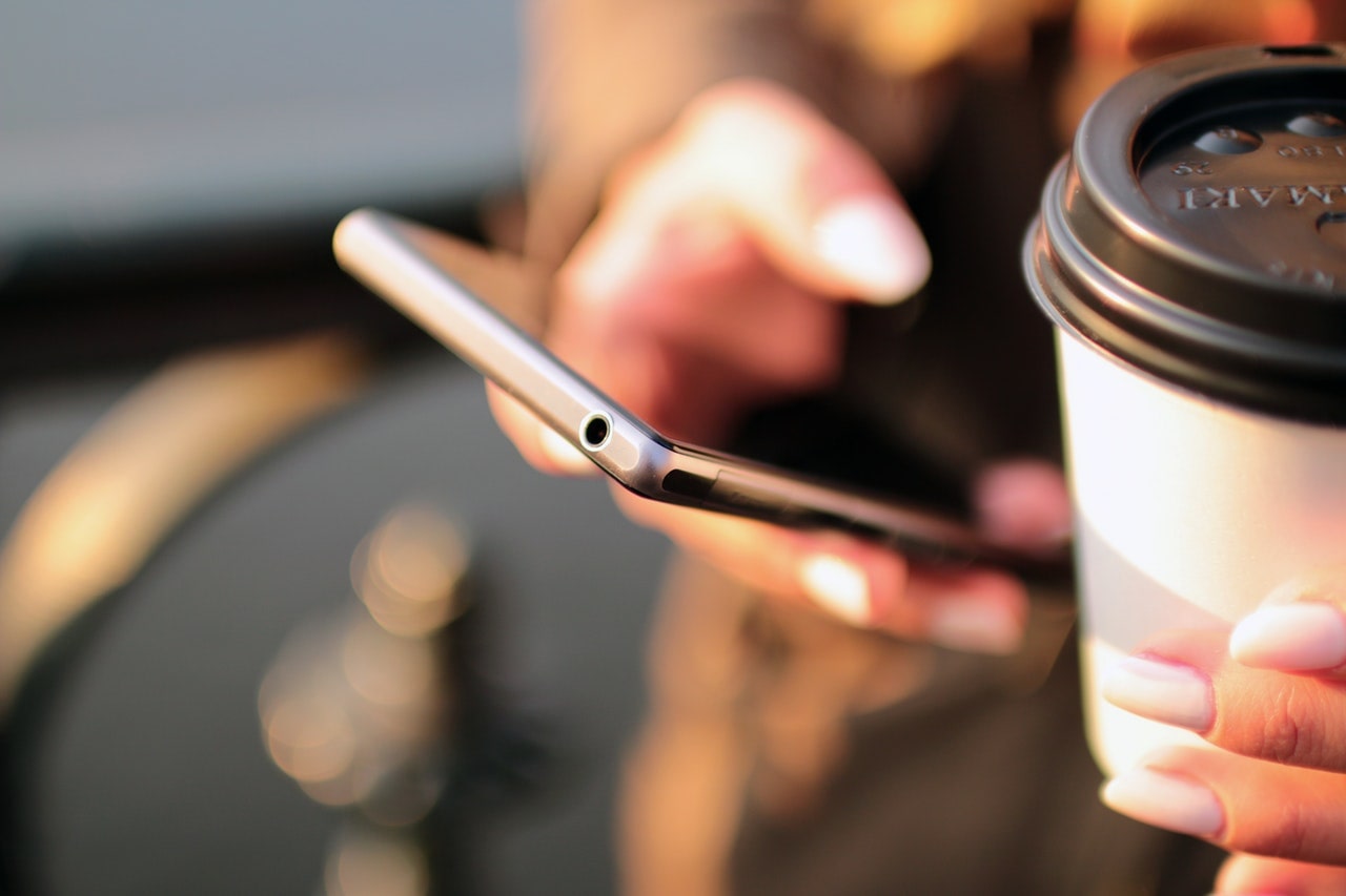 person holding phone and coffee